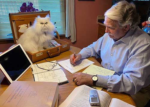 picture of attorney Mark E. Sostarich at his desk with his cat in a briefcase.