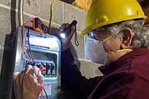 Photo of Mark E. Sostarich testing electrical board in a construction site